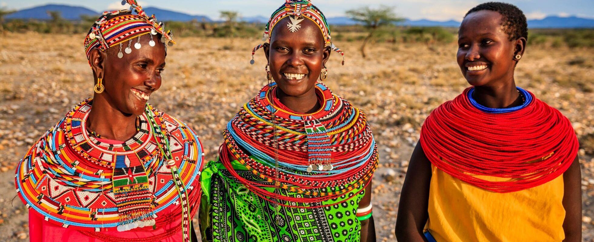 Drei afrikanische Frauen mit bunter Kleidung und Halsschmuck