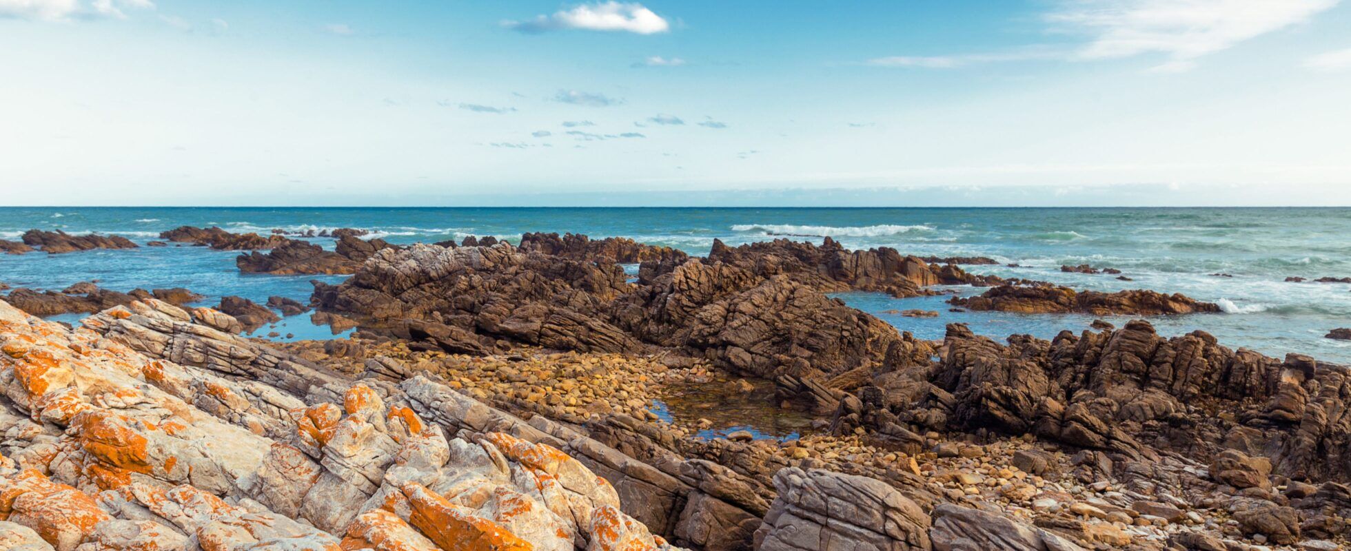 Rote Felsküste an blauem Meer des Agulhas Nationalparks