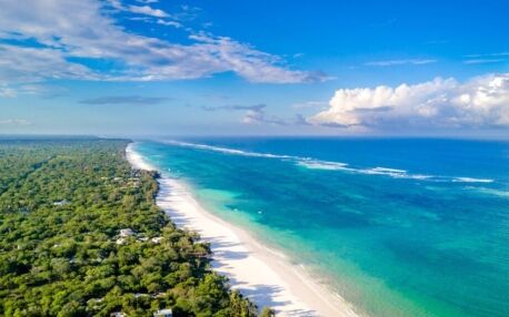 Weißer Sandstrand von Diani Beach mit Bäumen auf einer und dem blauen Meer auf der anderen Seite