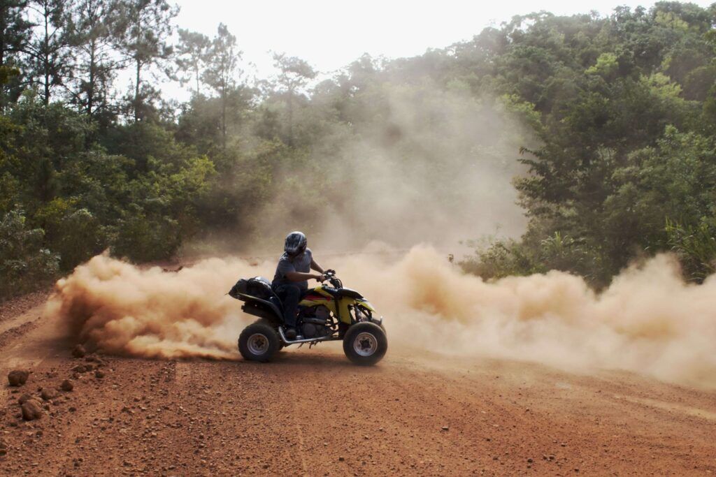 Ein Mensch auf einem Quad auf einer staubigen Straße mit einer Staubwolke