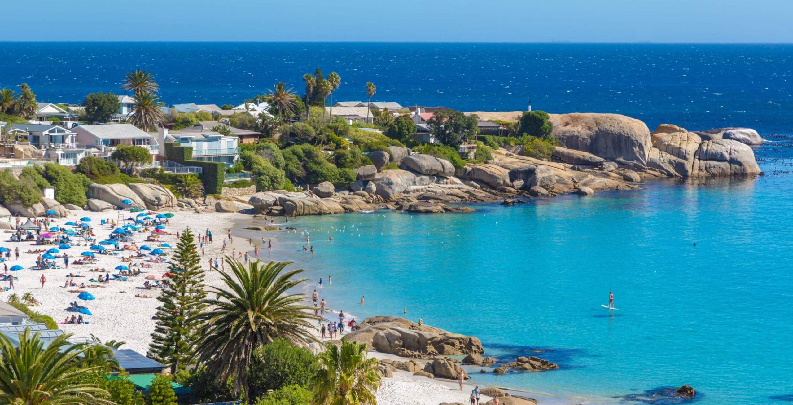 Camps Bay mit einer felsigen Küsten, Palmen und azurblauem Meer
