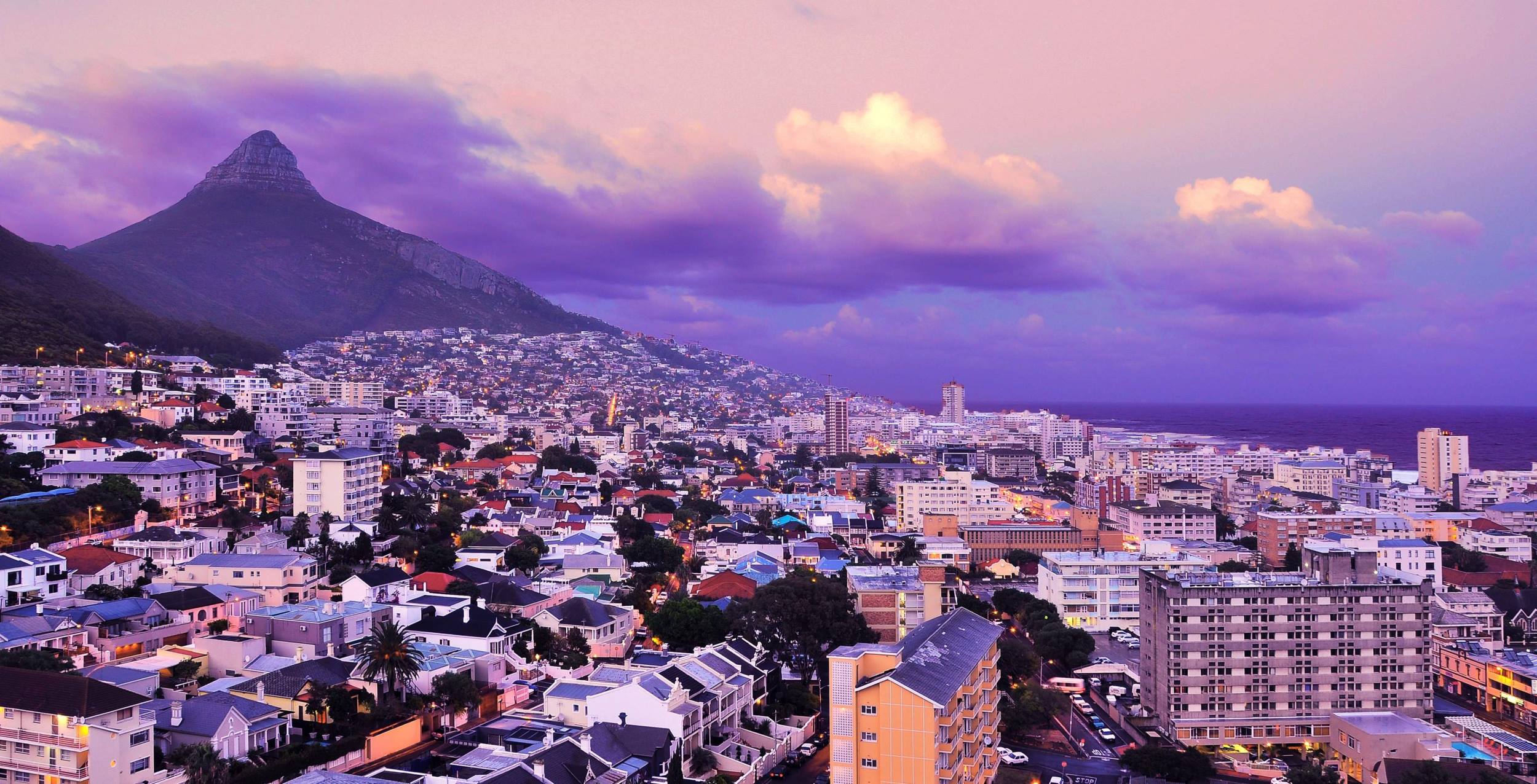 Kapstadt bei Sonnenuntergang und lilafarbenem Himmel mit einem Berg im Hintergrund