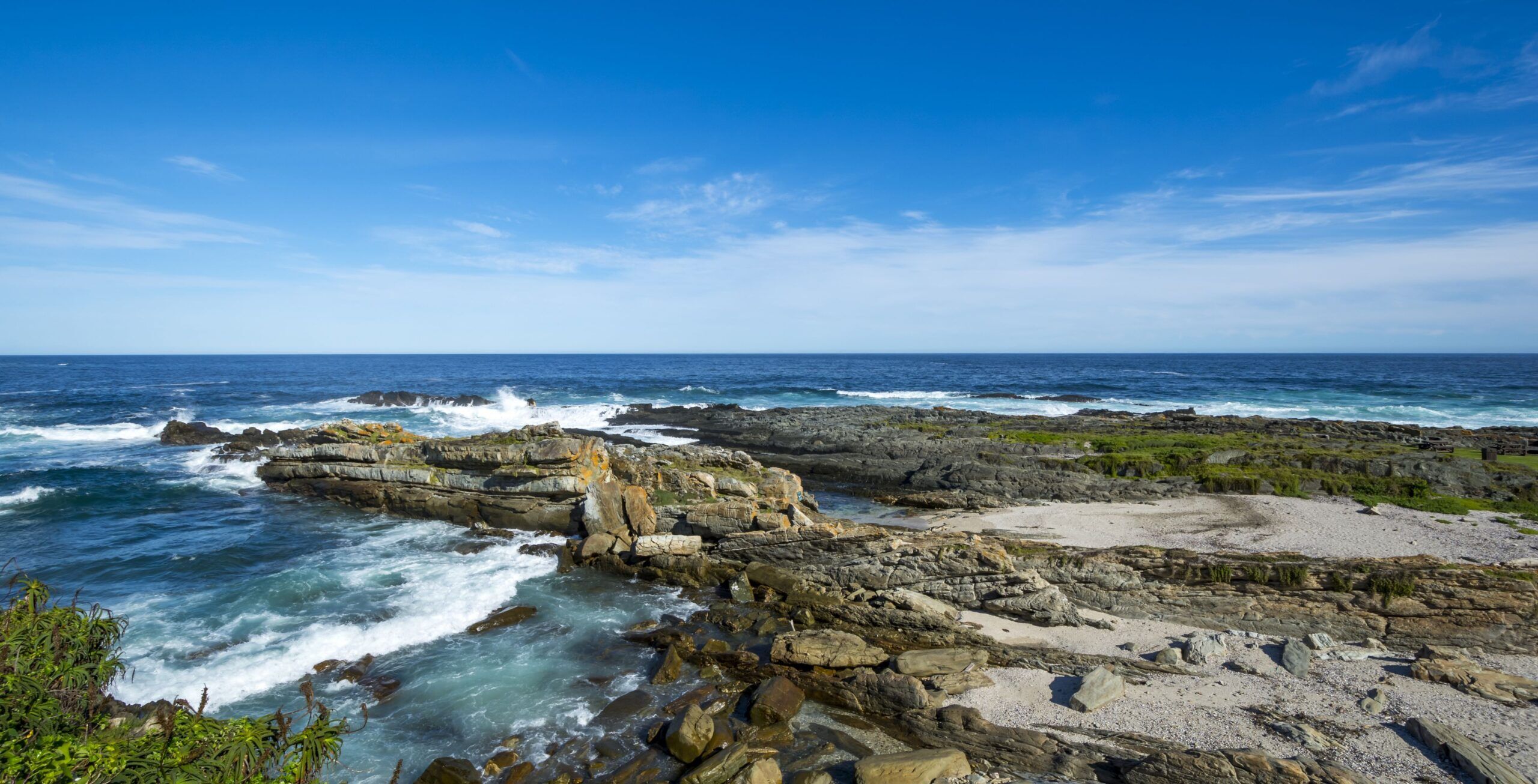 Felsige Küste mit blauem Meer und brechenden Wellen
