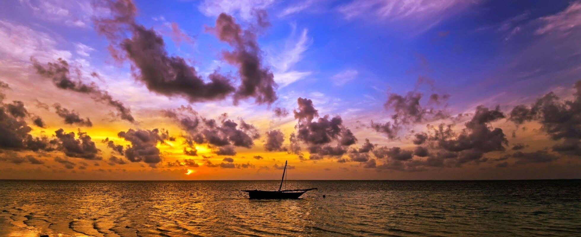 Boot auf Indischem Ozean bei Sonnenuntergang, Wolken am lila Himmel, Diani Beach