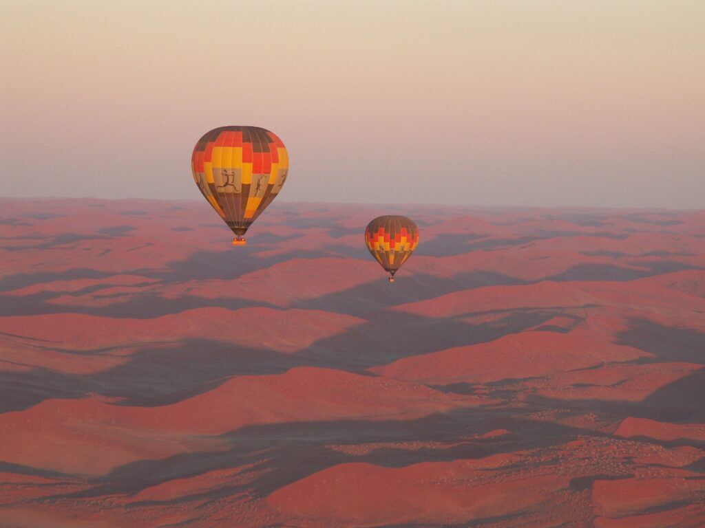 Zwei Heißluftballons bei Sonnenaufgang über der Namib Wüste