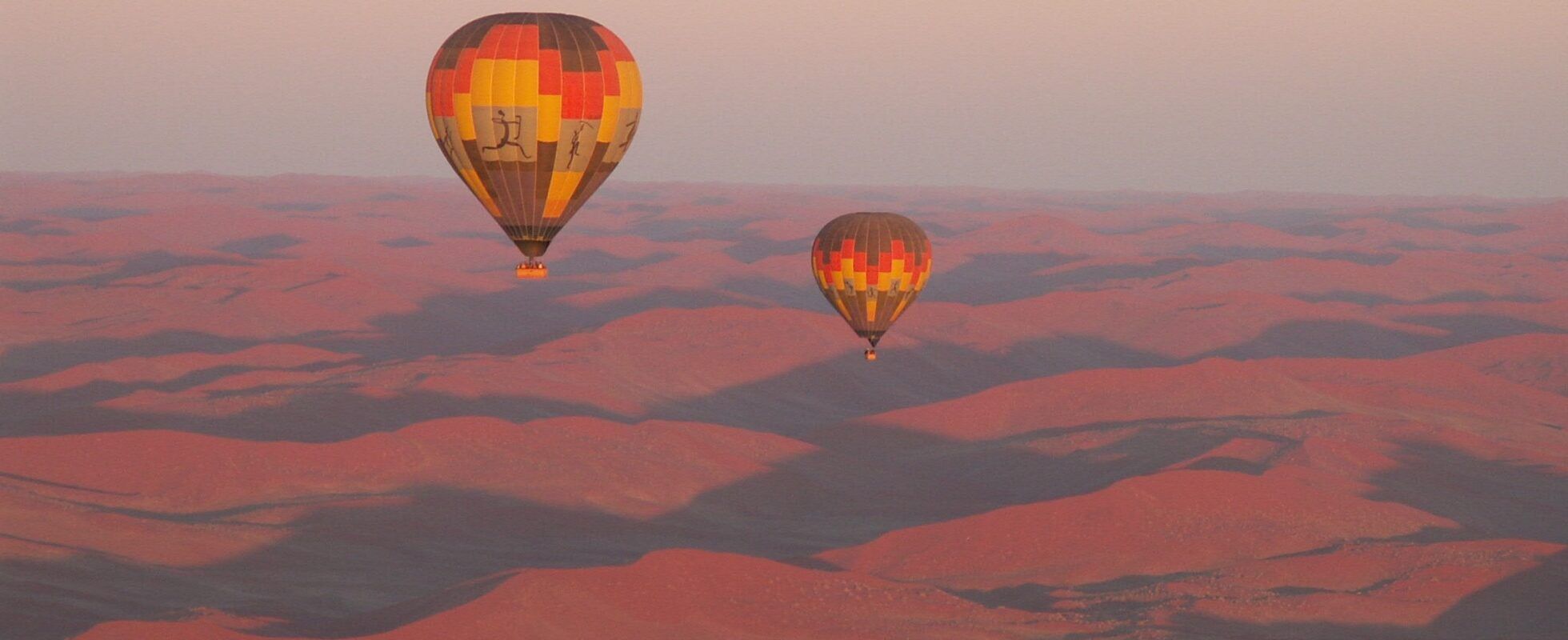 Zwei Heißluftballons bei Sonnenaufgang über der Namib Wüste