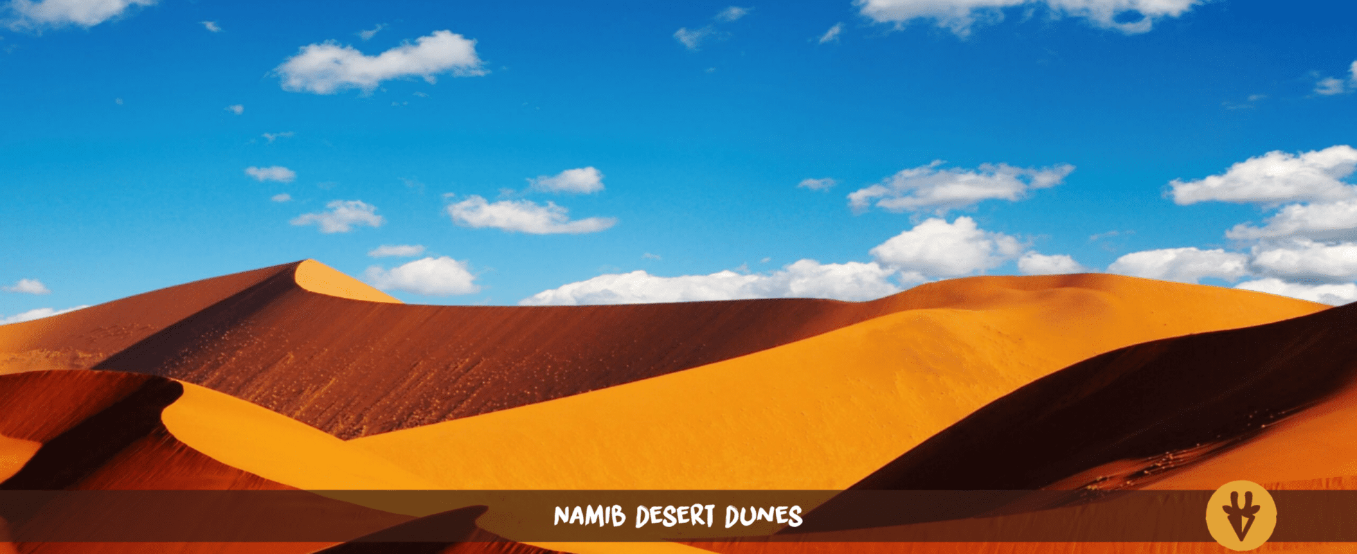 Wellenartige Dünen der Namib-Wüste unter blauem Himmel mit weißen Wolken